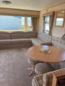 ein Wohnzimmer mit Sofa und Tisch in der Unterkunft Yellow 3 Caravan Ingoldmells 6 berth 3 bedrooms in Skegness
