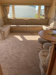 ein Wohnzimmer mit Sofa und Tisch in der Unterkunft Yellow 3 Caravan Ingoldmells 6 berth 3 bedrooms in Skegness + 20 Fotos