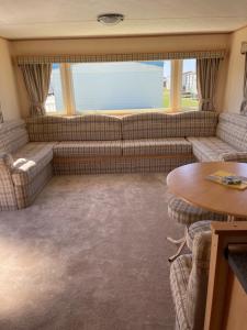 ein Wohnzimmer mit Sofa und Tisch in der Unterkunft Yellow 3 Caravan Ingoldmells 6 berth 3 bedrooms in Skegness
