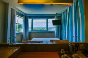 a room with a bed and a window with the ocean at Mercure Rio de Janeiro Barra da Tijuca in Rio de Janeiro