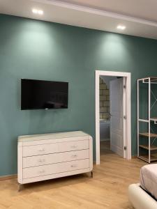een woonkamer met een tv aan een blauwe muur bij M&M Guest House in Ercolano