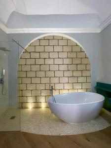 een wit bad in een kamer met een bakstenen muur bij M&M Guest House in Ercolano