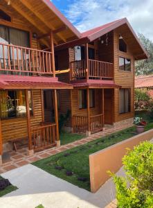 a log cabin with a porch and balcony at Clusia Lodge in El Copey