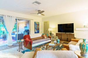 a living room with a couch and a tv at Beautiful Glam Mid-Century 1 block from Sarasota bay with Firepit in Sarasota