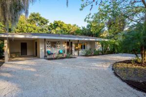 a house with a gravel driveway in front of it at Beautiful Glam Mid-Century 1 block from Sarasota bay with Firepit in Sarasota