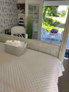 a white bed with a box on it next to a window at Allen Harbor Rentals in Harwich Port