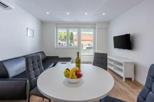 a living room with a white table with a bowl of fruit at Luxury Apartments Lovorka 1 & 2**** in Selce
