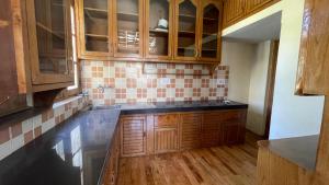 a kitchen with wooden cabinets and black counter tops at THE WILLOW HOUSE in Leh