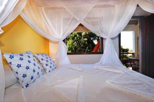 a bedroom with a white bed with a canopy at Pousada Arraial Colonial in Arraial d'Ajuda