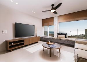 Il comprend un salon doté d'une télévision à écran plat et d'un canapé. dans l'établissement Gemini Resort with private pool and sea view, à Kalamaki