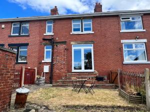 Cette maison en briques rouges dispose de fenêtres blanches et d'une terrasse. dans l'établissement Modern mid terrace villa, Royston, Barnsley, à Royston