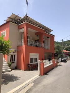 a red building with a balcony on a street at Spyridonou House in Parga