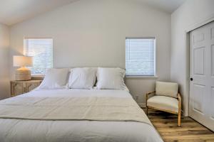 a bedroom with a bed and a chair and two windows at Close to Parks and Brews Sunny Grants Pass Apt! in Grants Pass