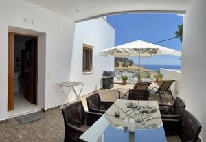 um pátio com uma mesa, cadeiras e um guarda-sol em Lindos Anatoli Luxury Villa em Lindos