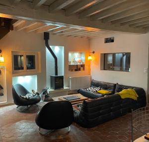 a living room with a leather couch and two chairs at Le QG 28 in Nonvilliers-Grandhoux
