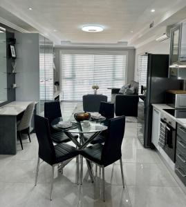 cocina y sala de estar con mesa de cristal y sillas en 515 The Granger, en Ciudad del Cabo