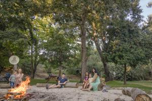 a group of people sitting around a fire in a park at Camping Dafna - By Travel Hotel Chain in Metsudat Menahem Ussishkin Alef