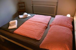 uma cama com lençóis e toalhas vermelhos e brancos em Mayers Swiss House, private home for 2-6 guests em Matten