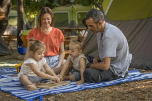 a man and two girls sitting on a blanket at Camping Dafna - By Travel Hotel Chain in Dafna
