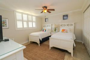 Un dormitorio con dos camas y un ventilador de techo. en Sand Dollar 1-105, en St. Augustine