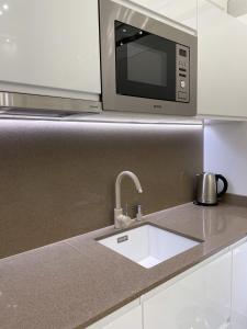eine Küchentheke mit einer Spüle und einer Mikrowelle in der Unterkunft St Stephen Luxury Apartment in Budapest