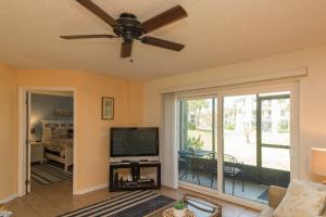 een woonkamer met een plafondventilator en een televisie bij Ocean Village Club F16 in St. Augustine