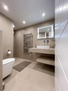 een badkamer met een wastafel, een toilet en een spiegel bij St Stephen Luxury Apartment in Boedapest