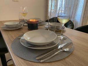 einen Holztisch mit Tellern und Gläsern Weißwein in der Unterkunft Várker 9 Apartman in Sopron