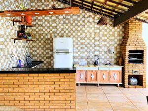 a kitchen with a white refrigerator and a brick wall at CASA DE PRAIA CORURIPE - LAGOA DO PAU in Coruripe