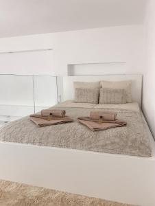 ein weißes Schlafzimmer mit einem großen Bett mit zwei Handtüchern darauf in der Unterkunft St Stephen Luxury Apartment in Budapest