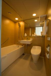 a bathroom with a tub and a toilet and a sink at JR Kyushu Hotel Blossom Shinjuku in Tokyo