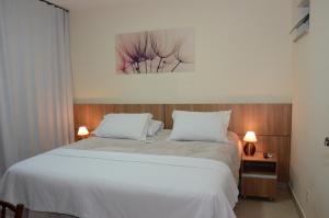 - une chambre avec un grand lit blanc et 2 oreillers dans l'établissement Hotel Monte Carlo, à São João del Rei