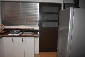 a kitchen with a stainless steel refrigerator and white cabinets at Langbeentjie Inn in Cape Town