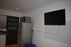 a kitchen with a refrigerator and a flat screen tv at Langbeentjie Inn in Cape Town