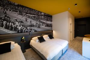 a bedroom with two beds and a painting of a baseball game at La Reine Hôtel - Restaurant , City Centre in Spa