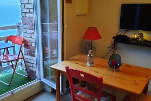 einen Holztisch mit einem roten Stuhl und einem Fenster in der Unterkunft Appartement pleine vue mer au bord de la plage in Binic