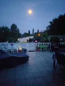 a patio with a table and a moon in the sky at Le soleil de provence in Peypin
