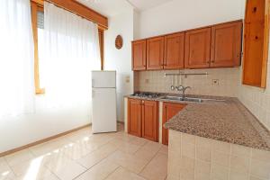 una cucina con armadi in legno e frigorifero bianco di Casa Michelle Otranto a Otranto
