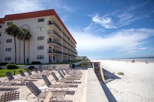 a beach with chairs and a building and the ocean at Hacienda del Sol II - 404 in New Smyrna Beach