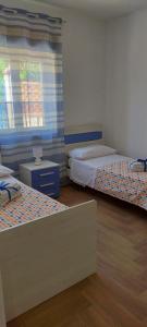 Leporano Marina的住宿－Casa vacanze Nonna Titina，客房设有两张床和窗户。