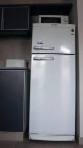 a white refrigerator with a microwave on top of it at Departamento Soberania totalmente amoblado in La Cieneguita