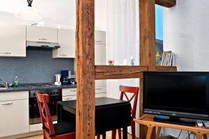 eine Küche mit einem Tisch und einem TV sowie eine Küche mit weißen Schränken in der Unterkunft Ferien auf Tippen Hof (Bleckede an der Elbe) in Bleckede