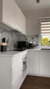 a white kitchen with white cabinets and a window at Domy na polanie- Szarotka in Wolany