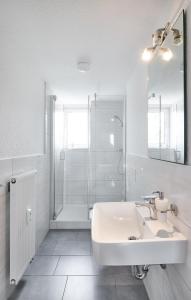 a white bathroom with a sink and a shower at Ferienwohnung im Leipziger Neuseenland in Böhlen