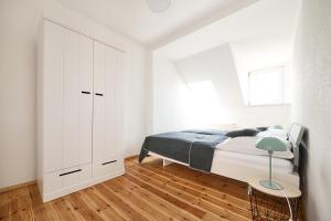 a white bedroom with a bed and a window at Ferienwohnung im Leipziger Neuseenland in Böhlen