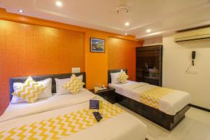 ムンバイにあるPANCHVATI RESIDENCY ANDHERI WESTのオレンジ色の壁の客室内のベッド2台