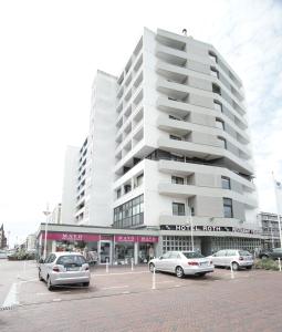 un parcheggio con auto parcheggiate di fronte a un edificio di Hotel Roth am Strande a Westerland