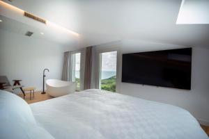 a white bedroom with a large bed and a large window at Hotel Boutique Berazadi Berri in Zarautz