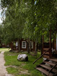 a building with a tree and a bench and a rock at Laumių Nameliai in Anykščiai