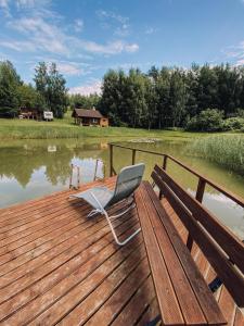 a chair sitting on a dock next to a lake at Laumių Nameliai in Anykščiai